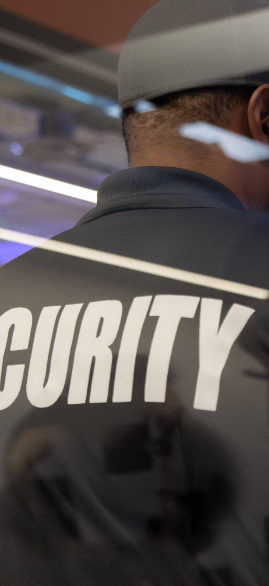 A security guard standing inside a commercial building nearby the window reflecting light